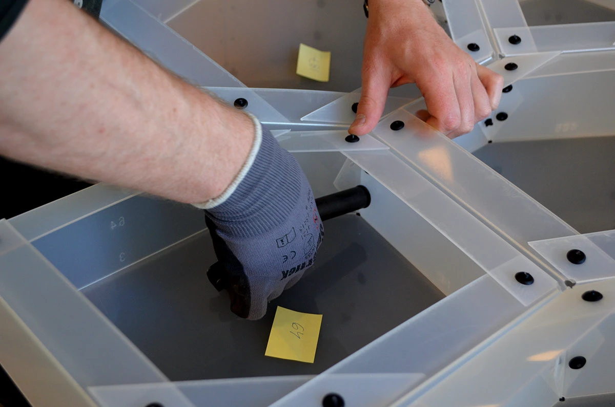 Close-up of plastic rivets being fitted to PolyShell modules.