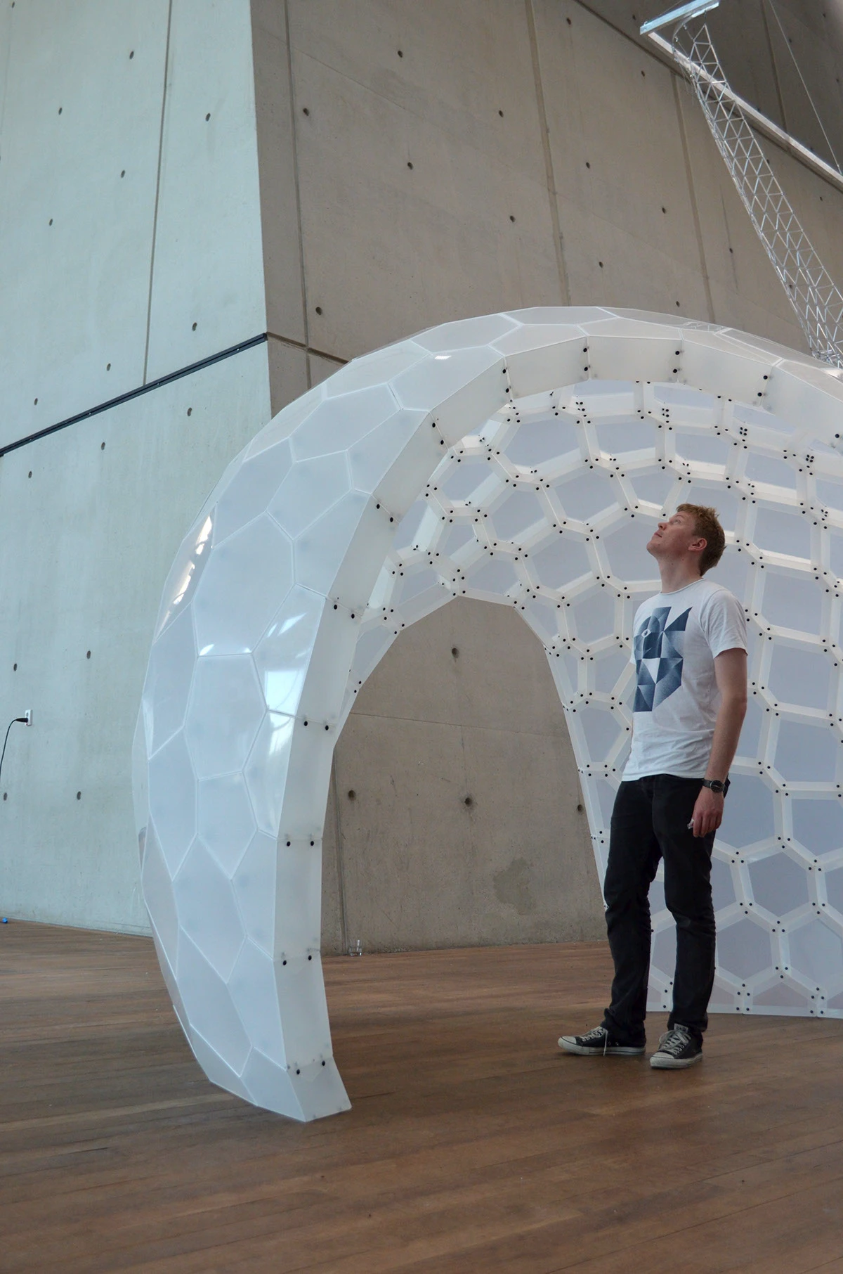 A person standing beneath PolyShell, showing the pavilion's scale.